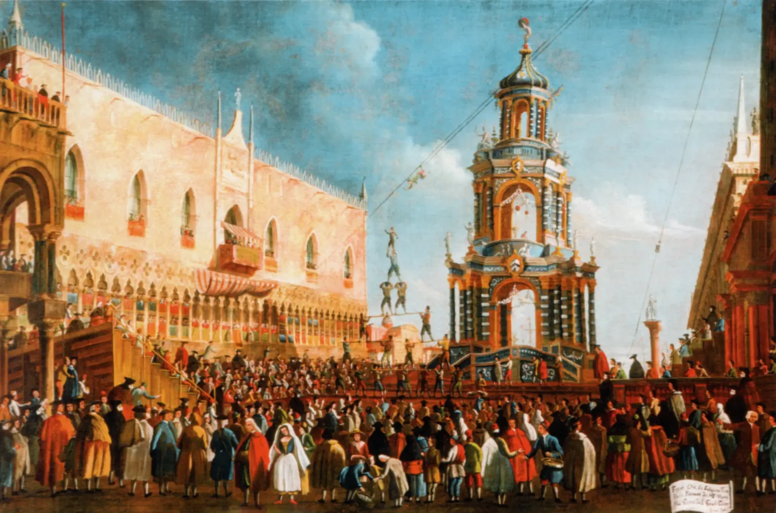 Oil painting of the feast of Fat Thursday during carnival. The space has the Doge's Palace on the left, and the Marciana library on the right, the view angled towards the palace. In the centre, a tall multi-story structure with resembles a tower. Lines across the square have a man suspended. Men forming a human tower is seen between the taller structure and the palace. The square is packed with people.